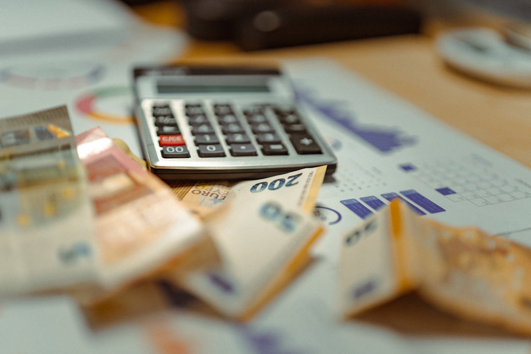 person holding paper near pen and calculator